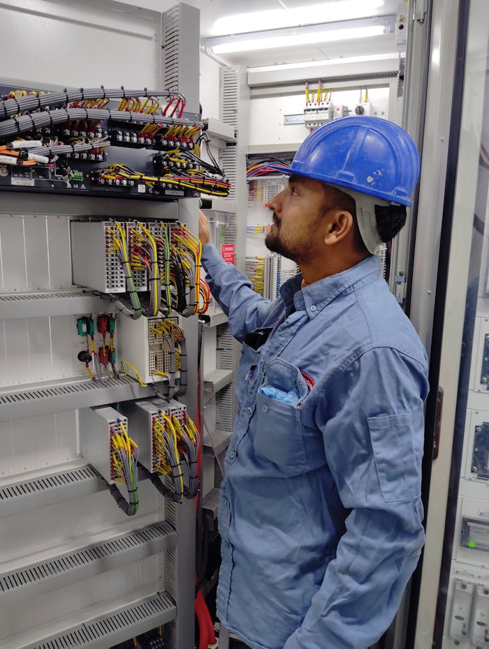 The Art of Drawing Readers In: Your attractive post title goes here Electrician in blue helmet checking control panel wiring for safety compliance.